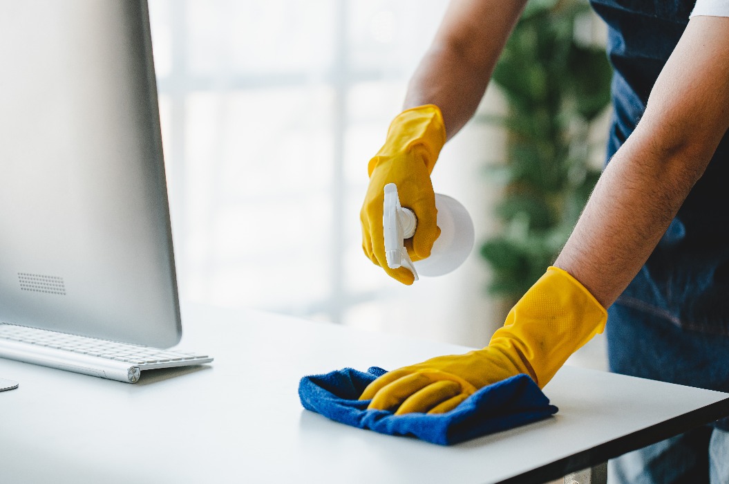 Das Reinigungspersonal verwendet Tücher und sprüht Desinfektionsmittel. Es wischt den Schreibtisch und den Boden im Büro ab. Reinigungspersonal. Reinigungskraft