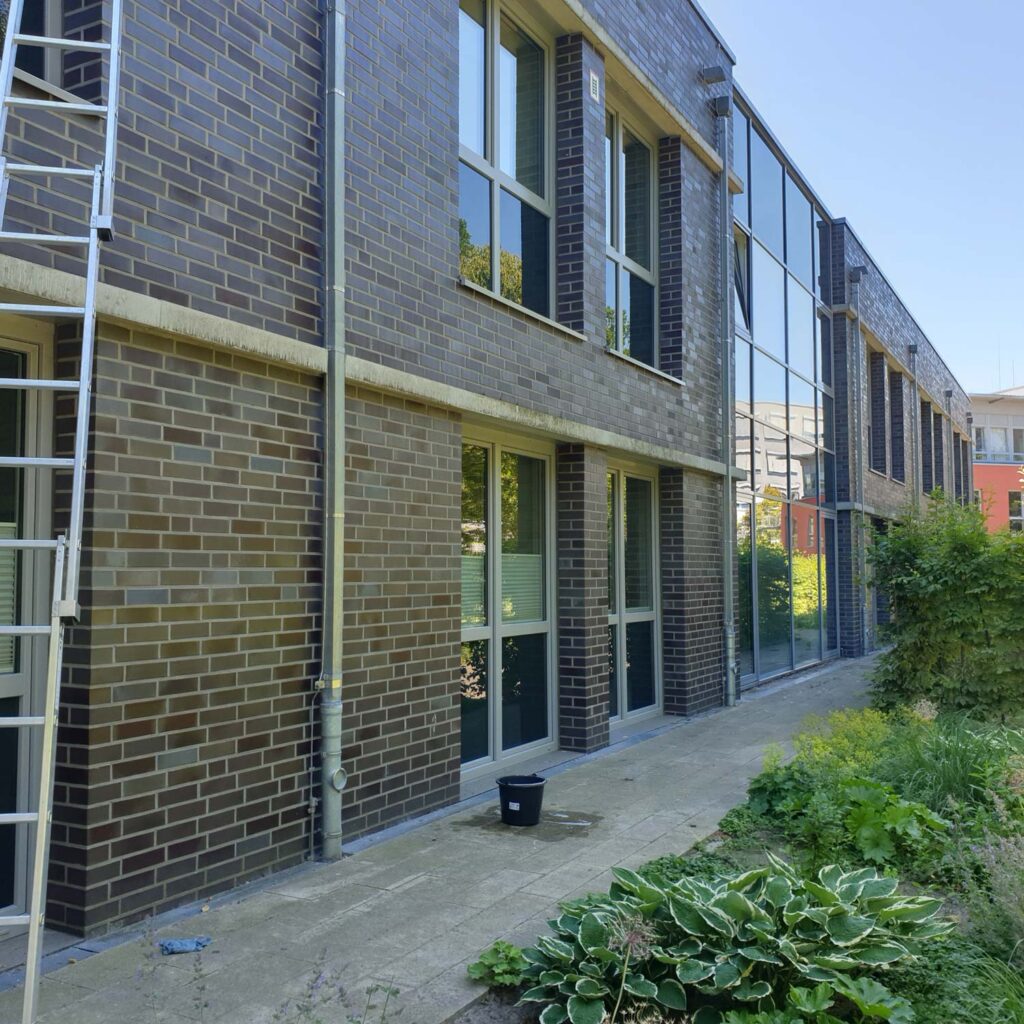 Moderne zweistöckige Fassade mit braunen Klinkersteinen und großen Glasfenstern